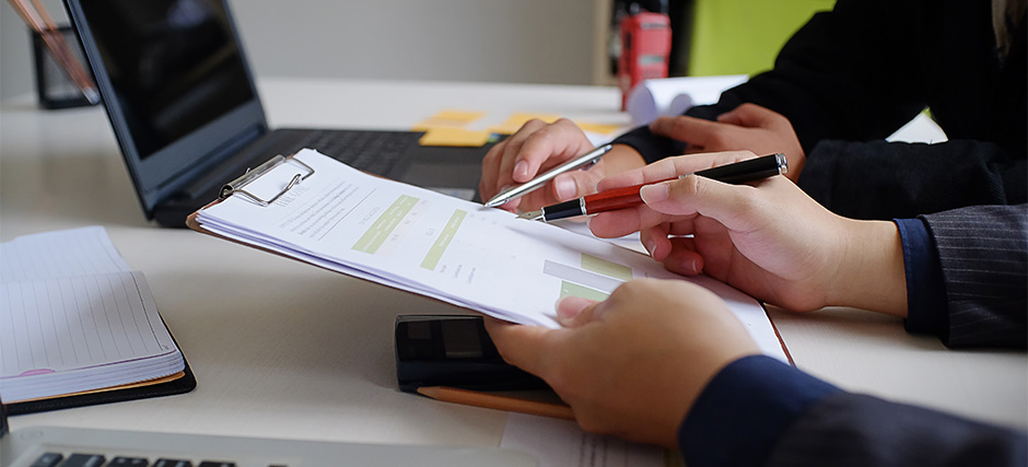 Two professionals reviewing and filling out a visitor registration form.