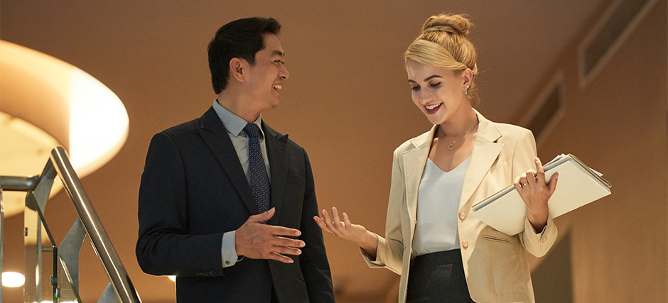 Guest attendee talking to a happy hotel guest on stairs.